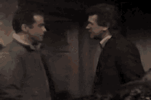 a man and a woman are kissing in a room while another man watches .