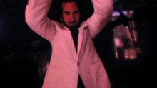 a man in a white jacket holds his arms up in the air