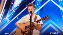 a young boy singing into a microphone while playing a guitar