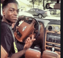 a young man is sitting in the driver 's seat of a car