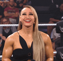 a woman in a black dress is smiling in a wrestling ring with the hashtag #thekom dresen