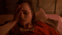 a woman laying on a bed with her hand on her head