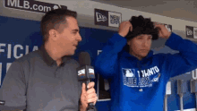 a man wearing a blue jays sweatshirt is being interviewed by two men
