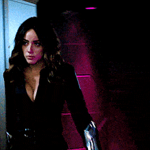a woman wearing a black jacket with a plunging neckline is standing in a dark room .