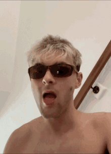 a shirtless man wearing sunglasses with his mouth open