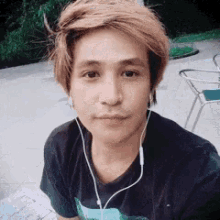 a young man wearing ear buds looks at the camera