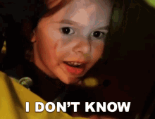 a little girl with blood on her face is making a funny face and saying i do n't know .