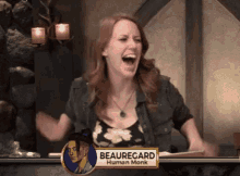a woman is laughing while sitting in front of a sign that says beauregard human monk