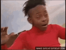 a young boy wearing a red sweater is making a funny face .