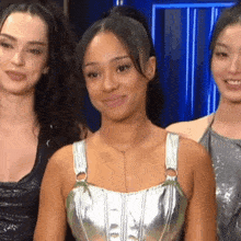 a woman in a silver top smiles while standing with two other women