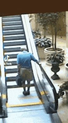 a man is walking down an escalator with a suitcase in his hand .