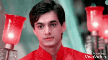 a young man in a red shirt is standing in front of a bunch of red lamps .