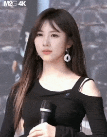 a woman in a black shirt is holding a microphone in her hand
