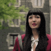 a woman in a red jacket is standing in front of a building