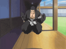 a man in a black kimono is kneeling down on a wooden floor