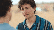a young man with curly hair is crying while talking to another young man