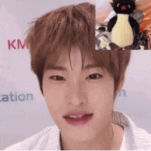 a close up of a person 's face with a stuffed penguin in the background .