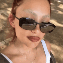 a woman wearing sunglasses and a necklace looks at the camera