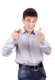 a young man in a striped shirt and jeans is giving a thumbs up .