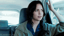 a woman sitting in the back seat of a car with blakehelp written on the bottom right