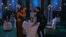a man and woman are dancing in front of a table with candles
