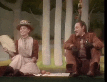 a man and a woman are sitting on a stage in a forest