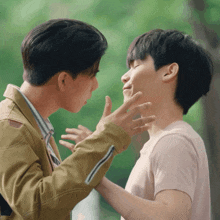 two men are touching each other 's faces and one of them is making a face