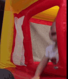 a child is playing in a red and yellow bouncy castle