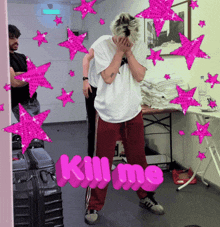 a man covering his face in front of a sign that reads kill me