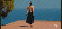 a woman in a black dress is standing on a beach looking at the ocean .