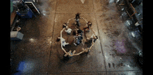 a group of women are dancing in a circle on a concrete floor