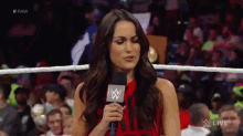 a woman in a red dress is holding a microphone with a w logo on it .