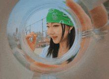 a woman wearing a green bandana is holding a glass