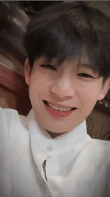 a young man in a white shirt smiles for the camera
