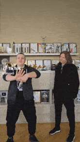 a man and a boy are dancing in front of a shelf full of trophies and awards