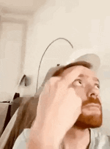 a man with a beard is wearing a hat and giving the middle finger .