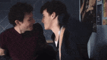two young men are sitting next to each other and laughing