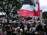 a crowd of people are gathered in front of a large flag