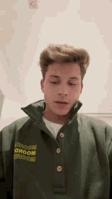 a young man wearing a green sweater with the word bloom on the front