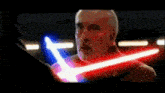a man with a beard is holding a red and blue lightsaber .