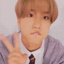 a man in a suit and tie is making a peace sign .