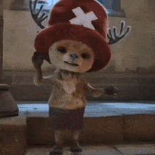 a stuffed animal wearing a red hat and antlers is standing on a set of steps .