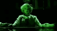 a woman is sitting at a table holding a man 's hand in a green light .