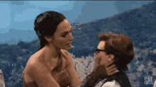 a woman is touching a man 's face in a snl scene .