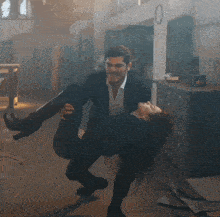 a man is carrying a woman in his arms in a room with a clock on the wall