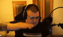 a man wearing headphones and glasses is sitting in front of a microphone and making a funny face .