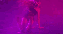 a woman is laying on her back on a stage in a purple light .