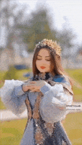 a woman wearing a crown and a dress is standing in a park .