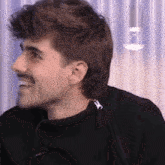 a man with a mustache is smiling and wearing a black shirt