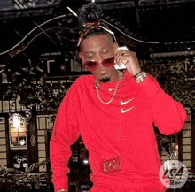 a man wearing a red nike sweatshirt is talking on his phone